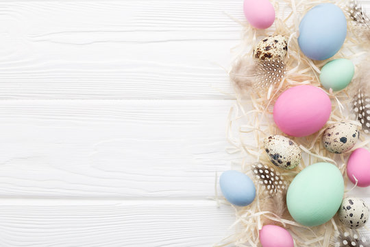 Easter frame with pastel colored eggs on white wooden table