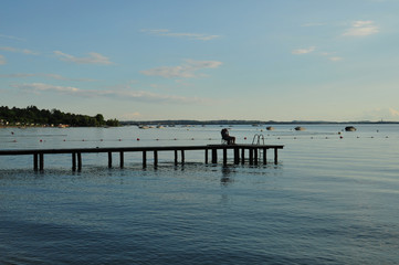 Fototapeta na wymiar Angler macht Pause auf einem Steg in den See