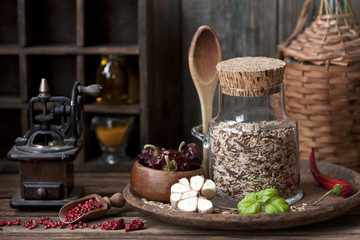 Close-up of mixed rice in glass bottle with garlic and red hot chili pepper on wooden background