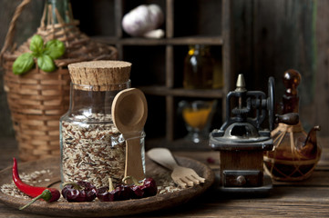 Close-up of mixed rice in glass bottle with garlic and red hot chili pepper on wooden background