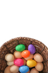 Brown eggs mixed with colorful Easter eggs in a wicker basket isolated pure white background top view shot vertical copy space at top