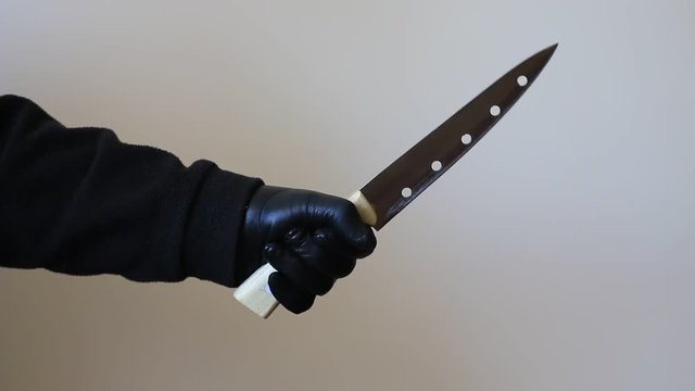 hand in leather gloves holding a big knife