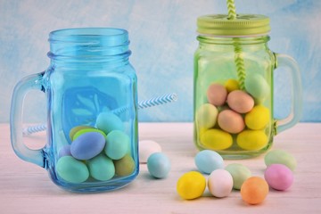 Sky-blue and green transparent glass jars with colored Easter eggs