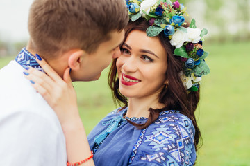 Obraz premium A close-up of a happy couple who are standing face to face. girl with a beautiful makeup and a wreath of flowers on the head