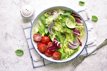 Vegan lunch bowl with salad leaves mix and vegetables (avocado and tomatoes) .Top view.