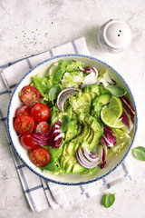 Vegan lunch bowl with salad leaves mix and vegetables (avocado and tomatoes) .Top view.