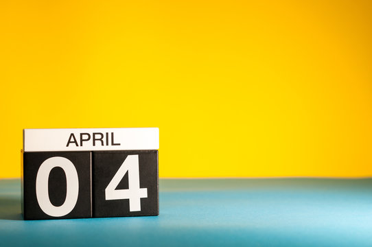 April 4th. Day 4 of april month, calendar on table with yellow background. Spring time, empty space for text