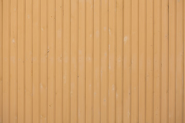 Fototapeta premium Wooden slats painted yellow. Wooden door gate yellow. Boards nailed together. Parallel vertical lines of boards