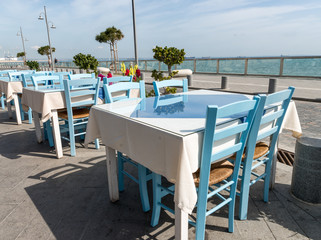 Several empty tables with chairs on the sea embankment