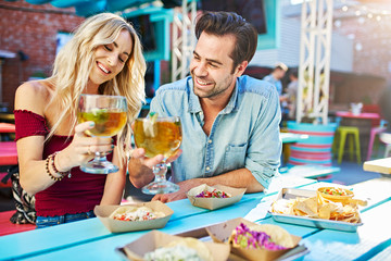 romantic couple making toast with beers at mexican restaurant