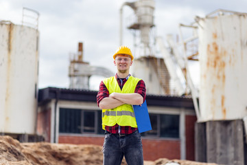 Confident male young worker in protective helmet taking notes
