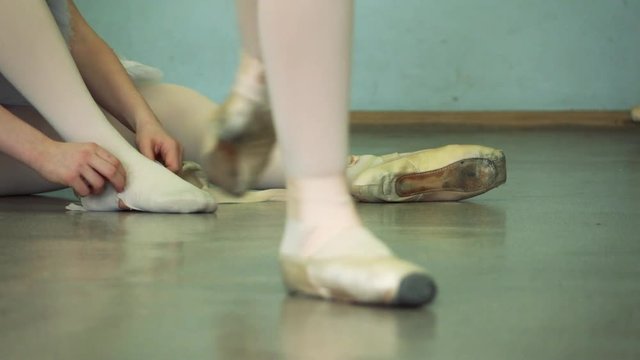 Slow motion footage. Ballerina wears ballet shoes on the background. Dansing foreground