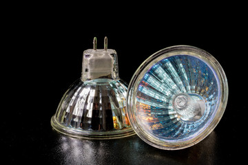 Halogen bulb in a reflective shade. Lighting accessories on a dark tole.