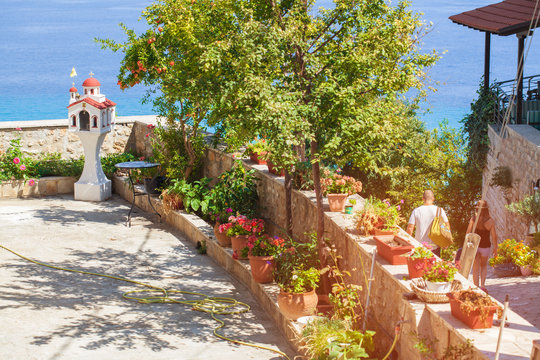 The Church monument stands on the terrace overlooking the sea. A bed of greenery outdoors.