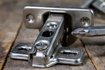 A woodwork hinge on a wooden workshop table. Joinery accessories for the construction of furniture in a carpentry workshop.