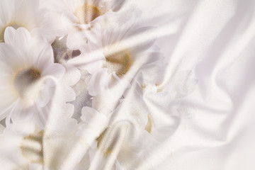 Fototapeta na wymiar White crumpled wrinkled fabric with waves and large white flowers, daisies, background crumpled tissue, double exposure photo .