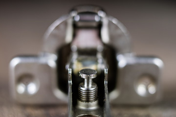A woodwork hinge on a wooden workshop table. Joinery accessories for the construction of furniture in a carpentry workshop.