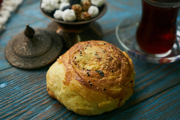 Novruz holiday with Azerbaijan national pastry Gogal and glass of black tea with traditional snack in silver bowl on wooden table background. Delicious dessert holiday food