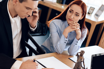 Man who divorces his wife consults on phone with lawyer. Disconcerted woman sits next to man talking on phone.