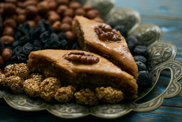 Novruz tray with Azerbaijan national pastry pakhlava and dry snack with nuts, kishmish, persimmon on rustic wooden blue background, close-up