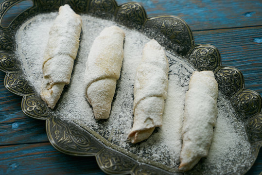 Biscuits with walnuts and sugar powder, oriental sweets mutaki pastry on rustic wooden blue table background, close-up