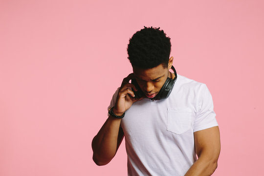 Portrait of a cool African American guy in white shirt on pink background
