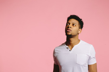 Portrait of a cool African American guy in white shirt on pink background