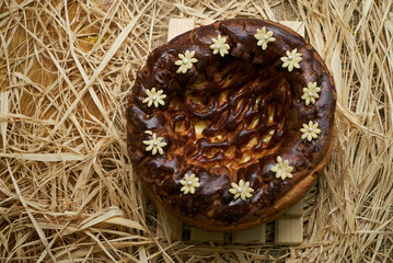 Traditional Ukrainian wedding bread korovai or karavai with decorations on rustic straw background. 