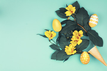 Happy Easter concept. Bouquet of green leaf with yellow spring's flowers and colorful easter eggs on blue background