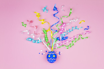 Happy Easter concept. Blue egg in waffle cone with colorful ribbons on center on pink background