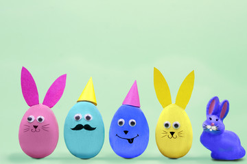 Happy Easter concept. Colorful easter eggs with comic fun faces and rabbit on blue background