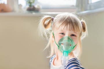 Happy smiling kid using nebuliser mask. Inhalation therapy curing chest cold and coughing....