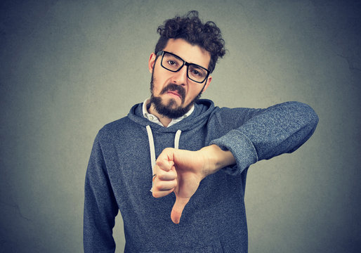 man in eyeglasses showing dislike with thumb down gesture