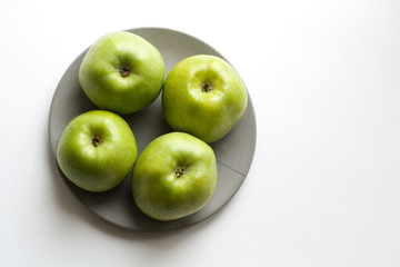 Four ripe green apples isolated on grey concrete plate from a high angle view