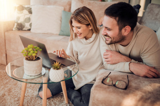 Young Couple Relaxing On Sofa With Laptop