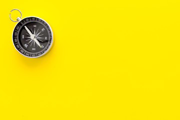 Compass on yellow background top view copy space