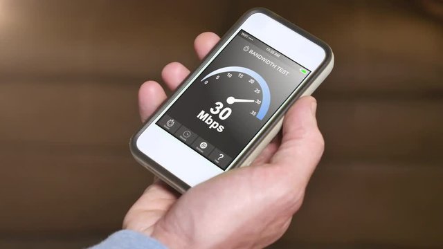A man tests his home Internet bandwidth by running a speed test app on his smartphone. Result is 30 Mbps.  	