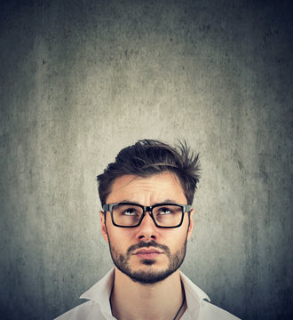 portrait of a doubtful man with glasses looking up