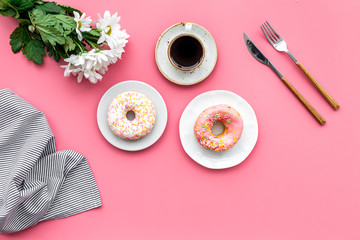 woman desk with flowers, coffee and donuts for breakfast in spring desing pink background flat lay mock-up