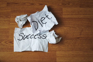 Crumpled papers with the word diet and succes on wooden background. The concept of refusing a diet.