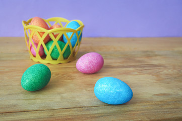 Colorful Easter eggs in basket on wooden background