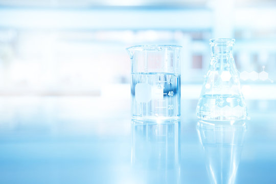 clear blue beaker and flask and chemical structure in research science laboratory background
