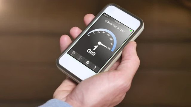 A man tests his home Internet bandwidth by running a speed test app on his smartphone. Result is 1 Gbps.  	