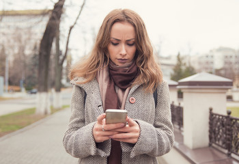 Sad girl using phone on street