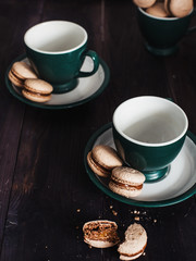 a tea party for two with green mugs and makaroons,  on a wooden background ,tasty dessert    beautifully in a row is located, the taste is evident