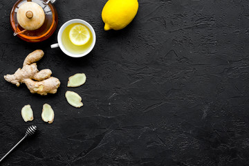 Tea for cure colds. Cup, teapot, ginger root and lemon on black background top view copy space