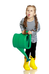 A little girl is watering a garden.