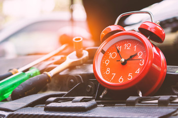 Red clock stand at the car with screwdriver.