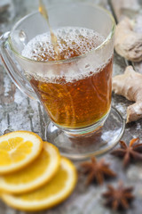 Arabic tea in traditional glass with mint, cinnamon, anise stars on grey wooden background
