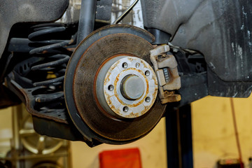 Rear brake disk with caliper partially removed about to be replaced